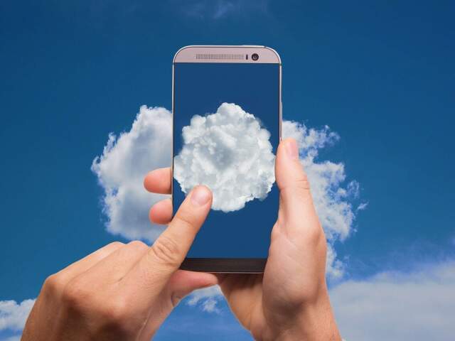Imagem mostra pessoa com celular na mão e mostrando nuvem